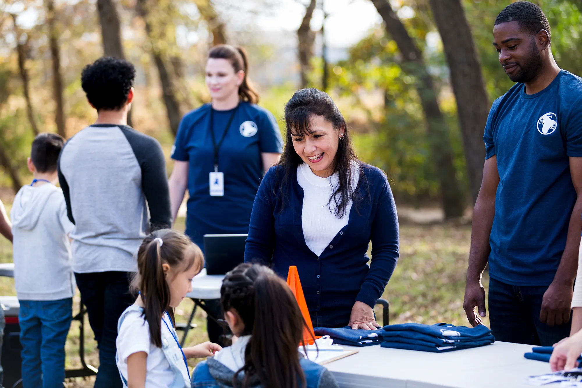 woman and man talking to children at a community service event