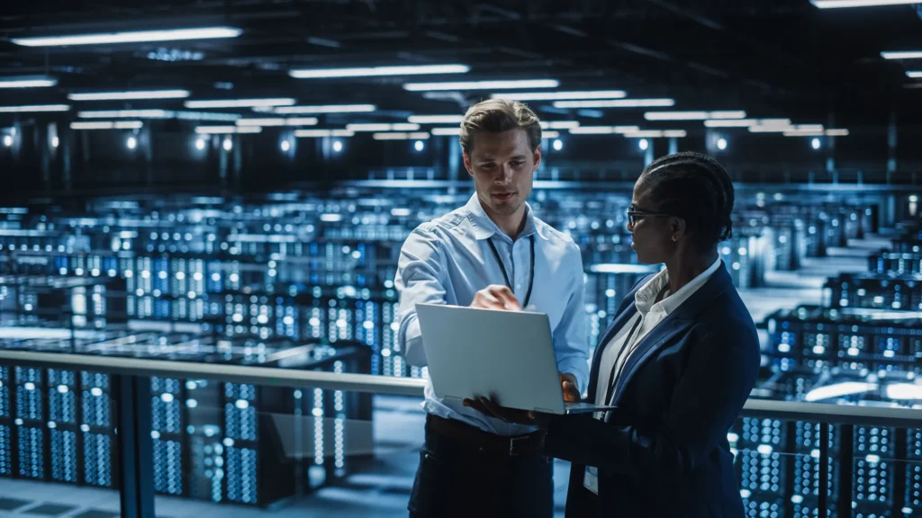 Man and a woman looking at a laptop screen inside a data center